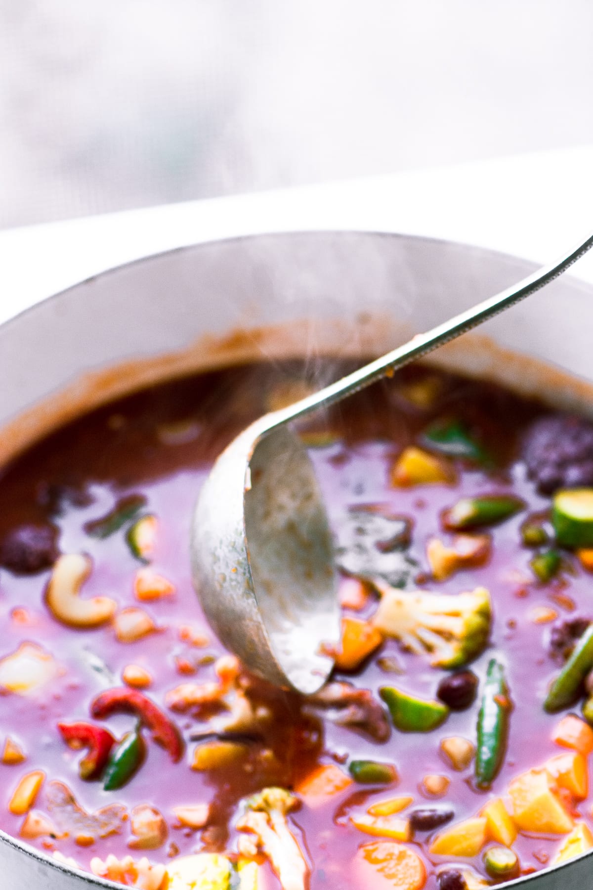 Minestrone classico in una pentola bianca con mestolo