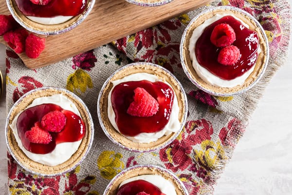Queste mini cheesecake al limone e lampone per la cottura saranno il tuo nuovo dessert estivo preferito. Un sacco di sapore di limone in grande stile confezionato in un mix cremoso di cheesecake e condito con marmellata di lamponi e lamponi freschi. È il mix perfetto di agrodolce!
