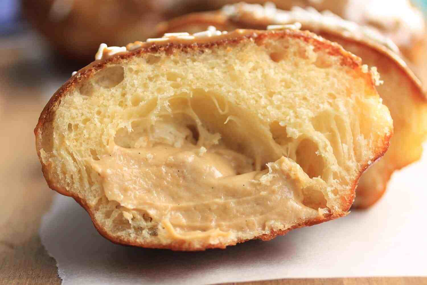 Ciambelle al caramello con crema di zucchero di canna da Sugar Salt Magic. Soffici ciambelle morbide con glassa al caramello dolce e ripieno di crema pasticcera
