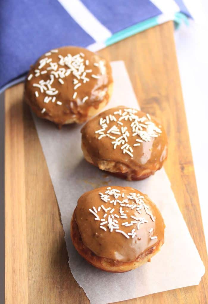 Ciambelle al caramello con crema di zucchero di canna da Sugar Salt Magic. Soffici ciambelle morbide con glassa al caramello dolce e ripieno di crema pasticcera