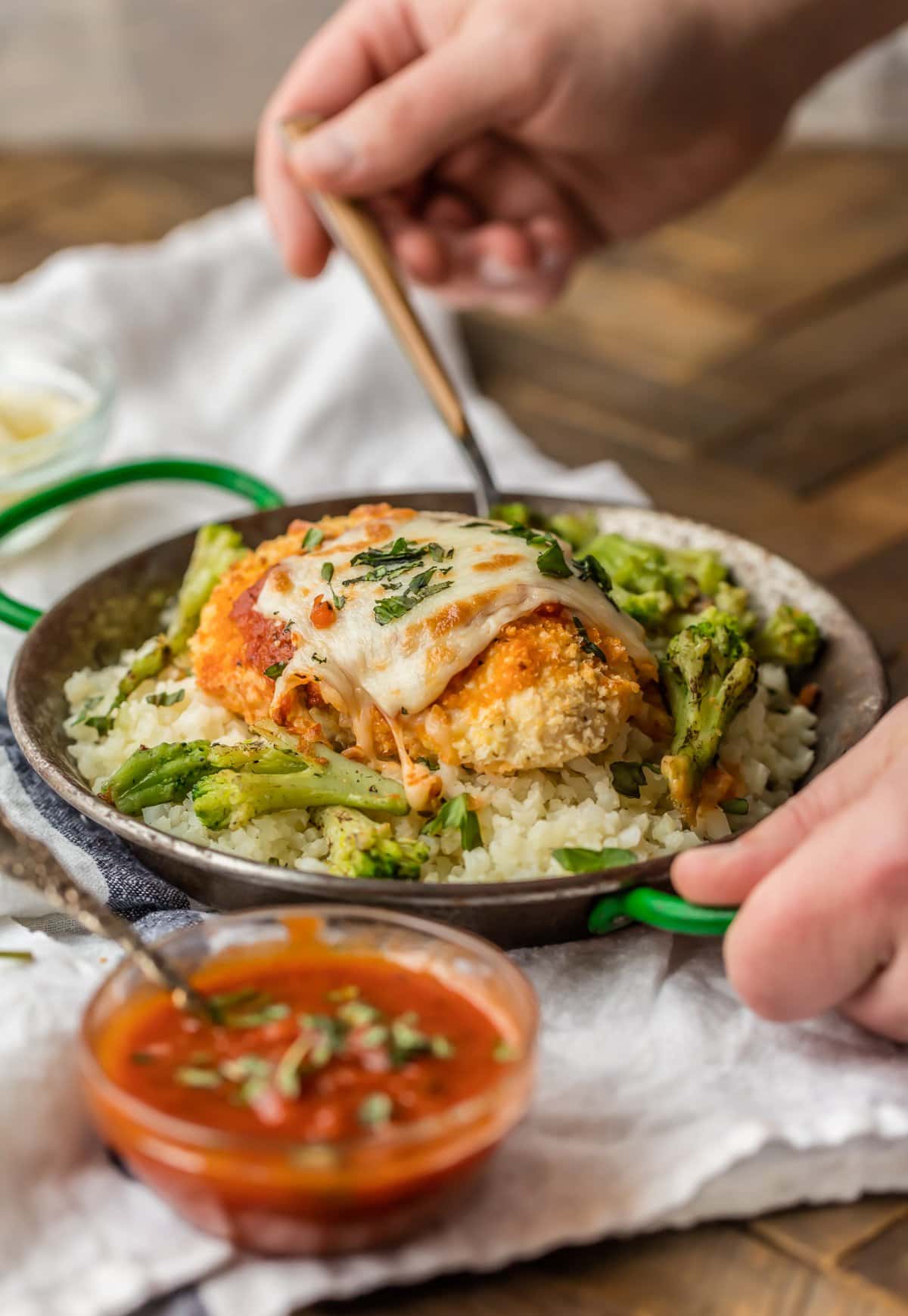 Questo PARMESAN DI POLLO AL FORNO con cavolfiore su ricetta di riso è MOLTO facile e un favorito della famiglia istantanea. Parmigiano di pollo sano e facile da cuocere condito con marinara, mozzarella al miele e basilico fresco. Una ciotola piena di riso con cavolfiore e parmigiano di pollo al forno