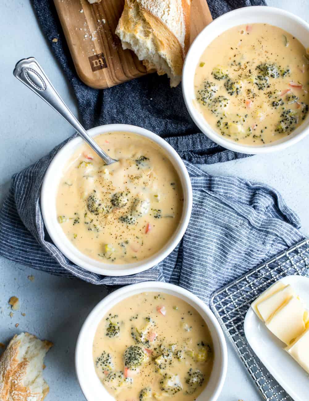 Ciotole di formaggio e broccoli disposti accanto a pane e burro