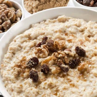 una ciotola di farina d'avena condita con uvetta, noci e zucchero di canna