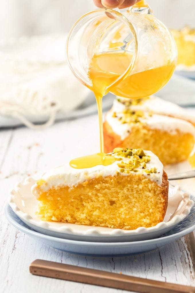 Versare lo sciroppo d'arancia su una fetta di torta su un piatto bianco