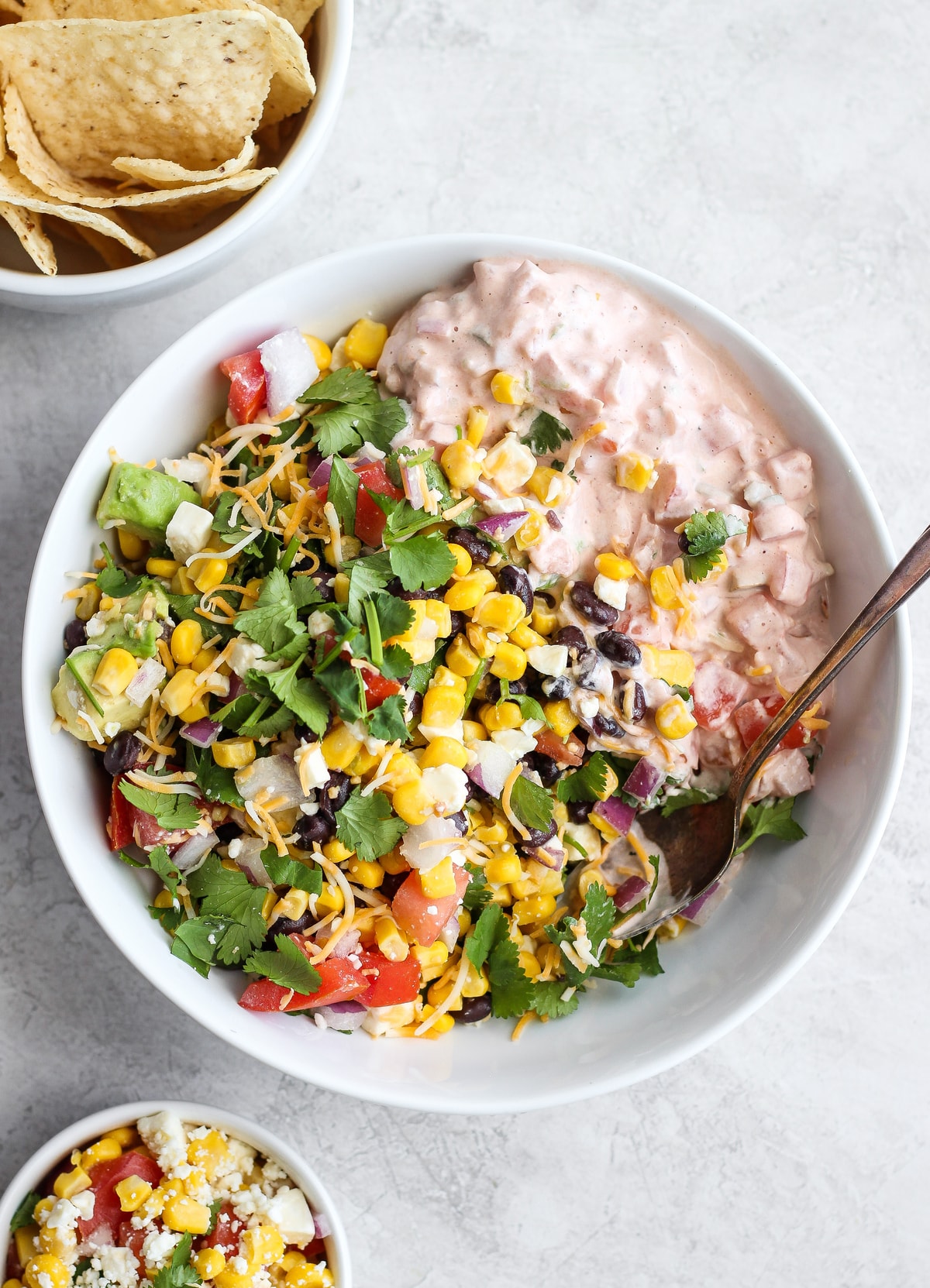 tazón blanco grande lleno de frijoles negros, maíz, tomates, aguacate, salsa, aguacate y más