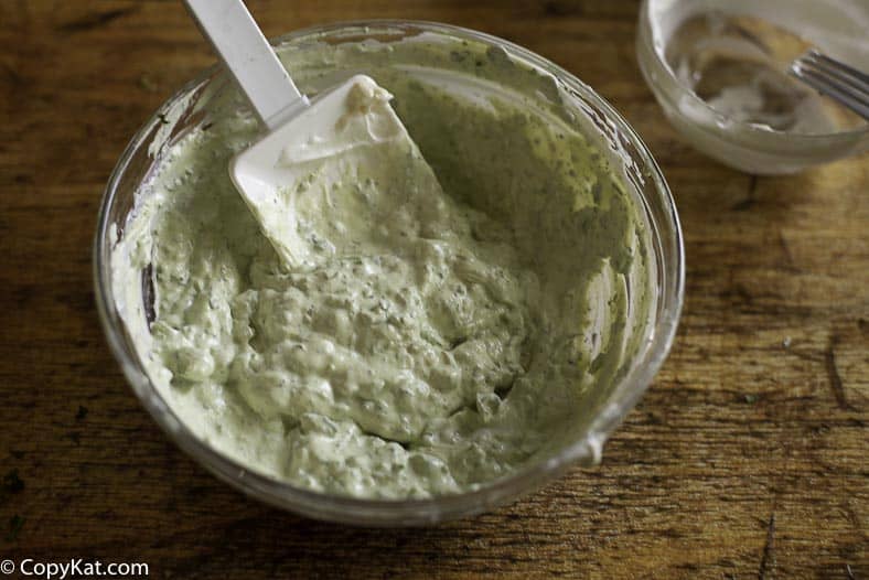 Mescola panna acida, maionese, avocado e altro per guarnire la dea verde.