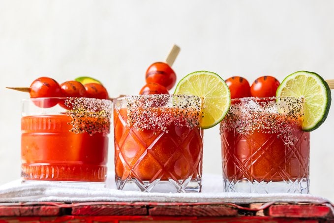 3 vasos cortos con bordes de sal y chile en polvo, rellenos de margaritas de tomate