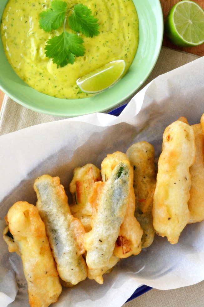 Foto aerea di birra pasticciata di zucchine e una ciotola di lime e coriandolo aioli.