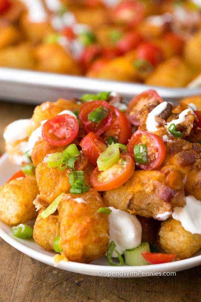 Los Nachos Tater Tot tienen crujientes Tater Tots cubiertos con queso cheddar derretido y tocino. ¡Esta merienda toma solo unos minutos para prepararse y es amada por absolutamente todos!