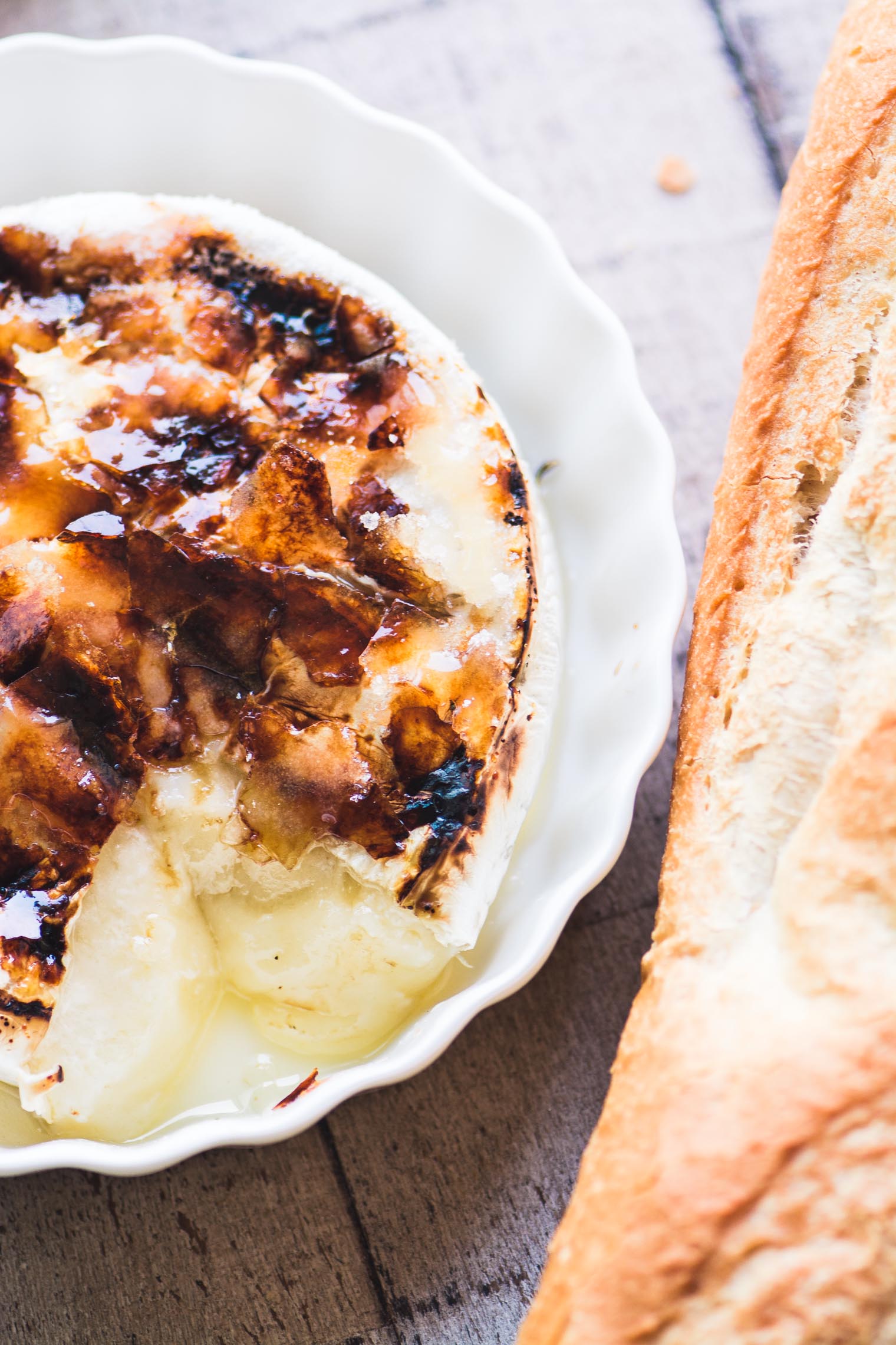 Brûléed Brie ~ este es tu aperitivo para la temporada ~ solo necesitas una rueda de Brie y un poco de azúcar para hacer esto, y los resultados hablan por sí mismos. #bakedbrie #bakedcheese #appetizer #holidayappetizer #easyholidayappetizer #thanksgivingappetizer #Christmasappetizer #brulee #caramel #bestbakedbrie #amazingappetizer #bakedbrierecipe Bruleed Brie al horno en un plato blanco