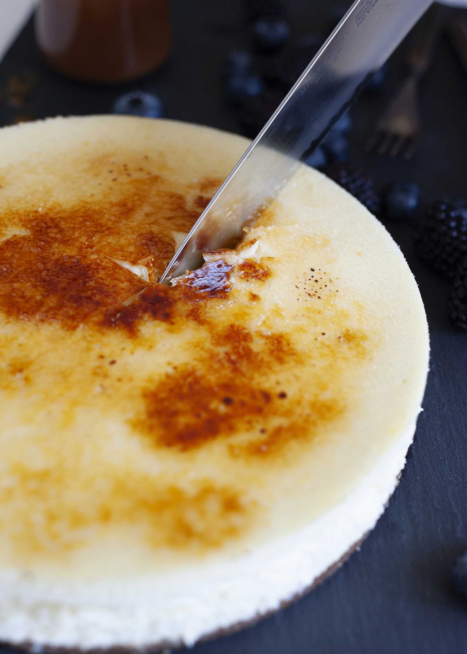 Un coltello che taglia il fragile condimento della migliore cheesecake con crema di bruelee