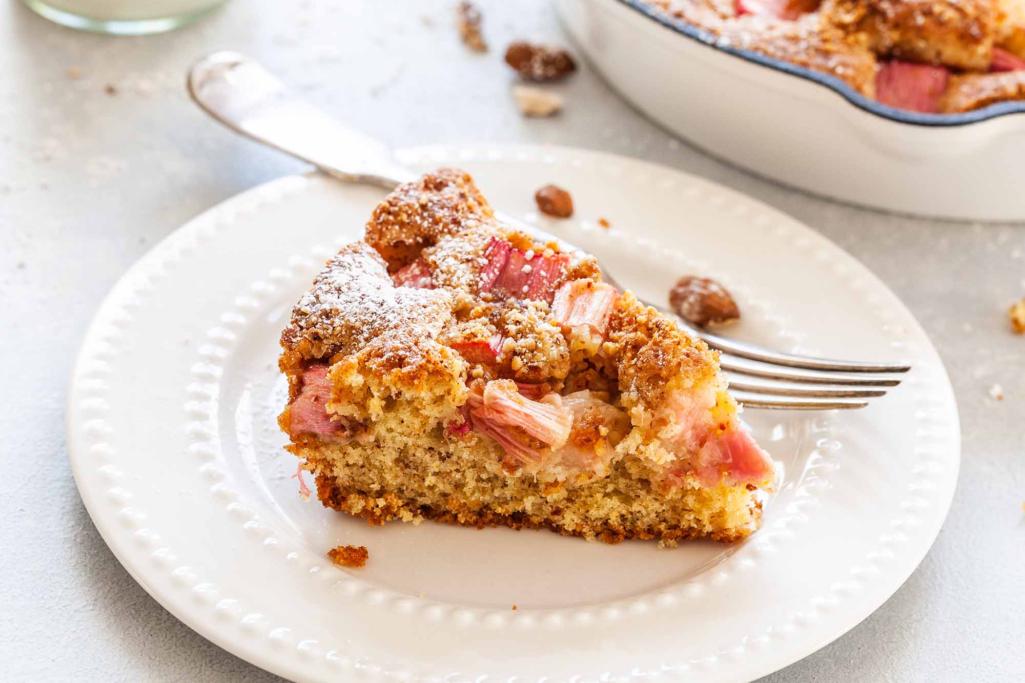 Torta di farina di mandorle con rabarbaro - fetta di torta di mandorle su un piatto bianco