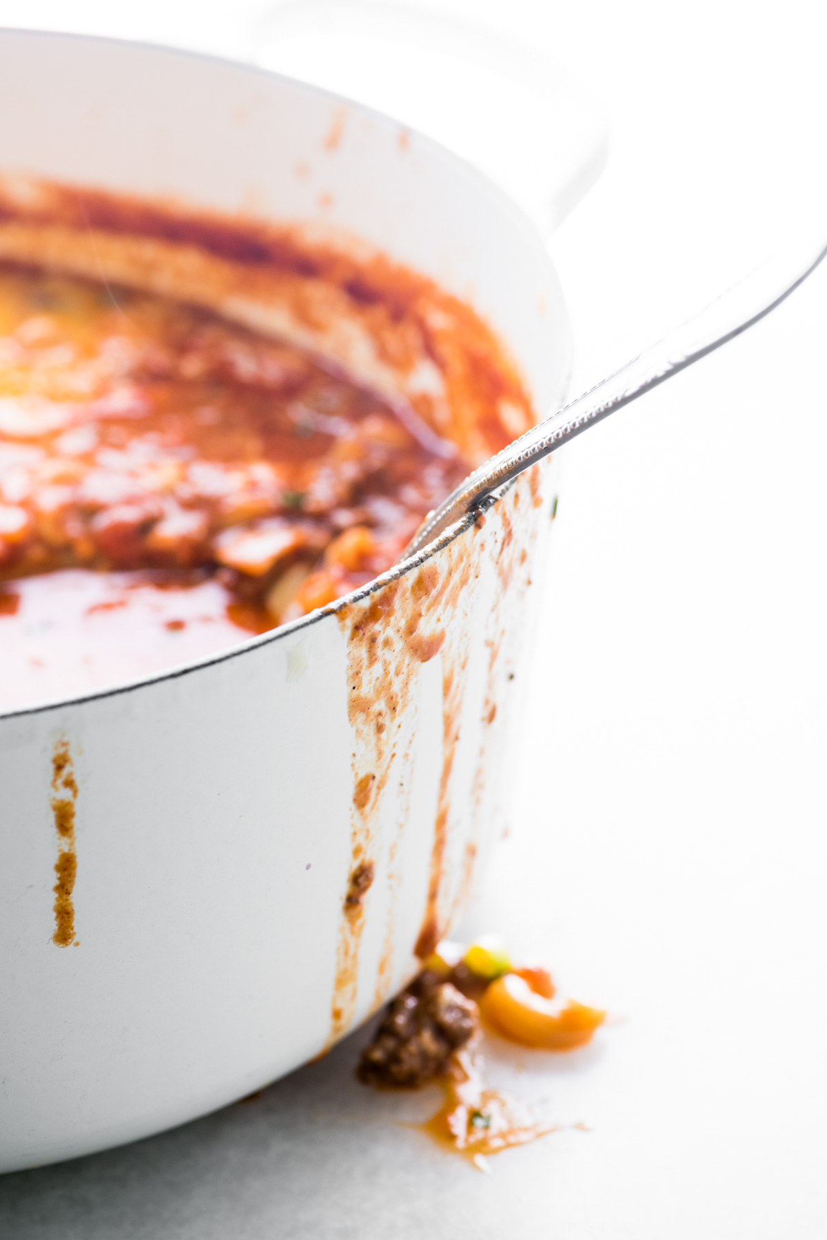 una pentola bianca con chili mac gocciolante lungo i lati