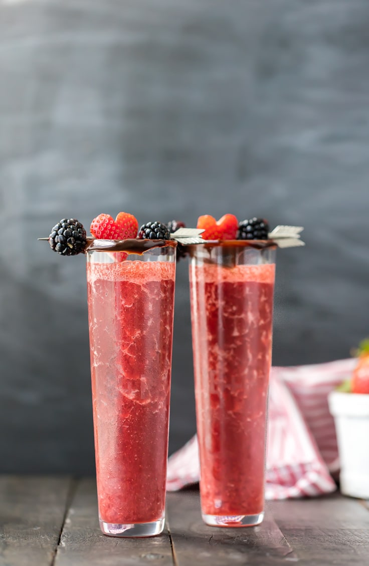 due bicchieri alti e sottili pieni di cocktail al cioccolato con fragole ricoperti di cioccolato e conditi con bacche