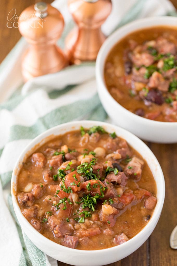 due scodelle e zuppa di fagioli e prosciutto guarnita con prezzemolo