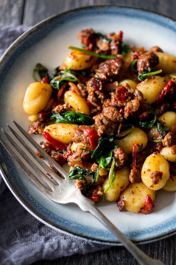 Questo gnocchi di spinaci con peperoncino arrostito e chorizo ​​è il pasto perfetto di 20 minuti nei giorni feriali. Ricco di sapore e semplicissimo da realizzare. Tutta la tua famiglia adorerà questo piatto!