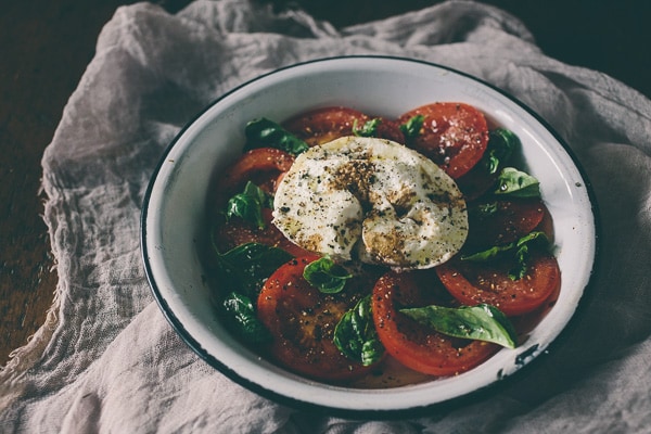 Questa insalata caprese alla burrata è il piatto estivo perfetto. Pomodori freschi e carnosi conditi con olio d'oliva, aceto balsamico e serviti con burrata fresca e basilico. 