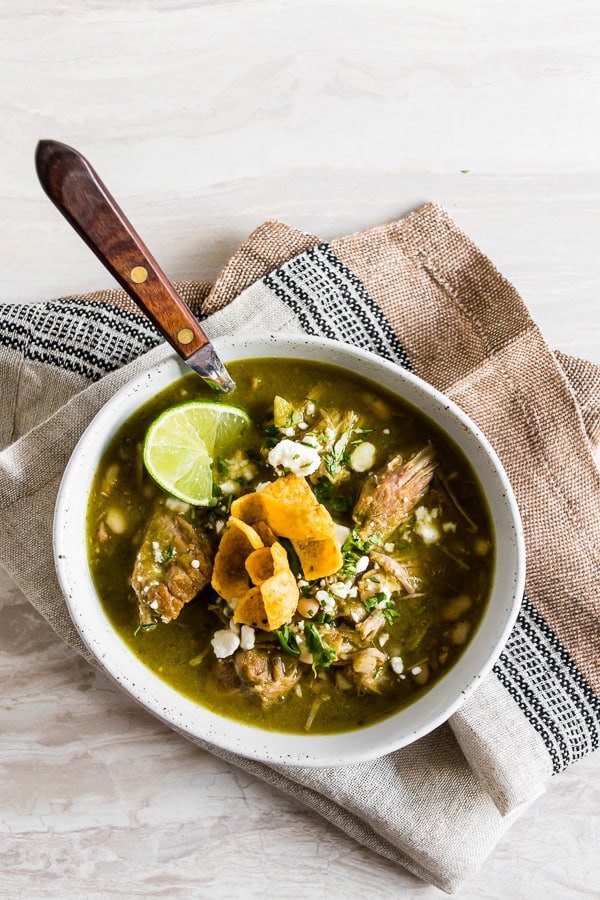 Questo chili di maiale verde istantaneo è fatto con coriandolo, tomatillos, aglio, maiale e fagioli bianchi morbidi. Ottimo se condito con formaggio cotija e patatine croccanti!