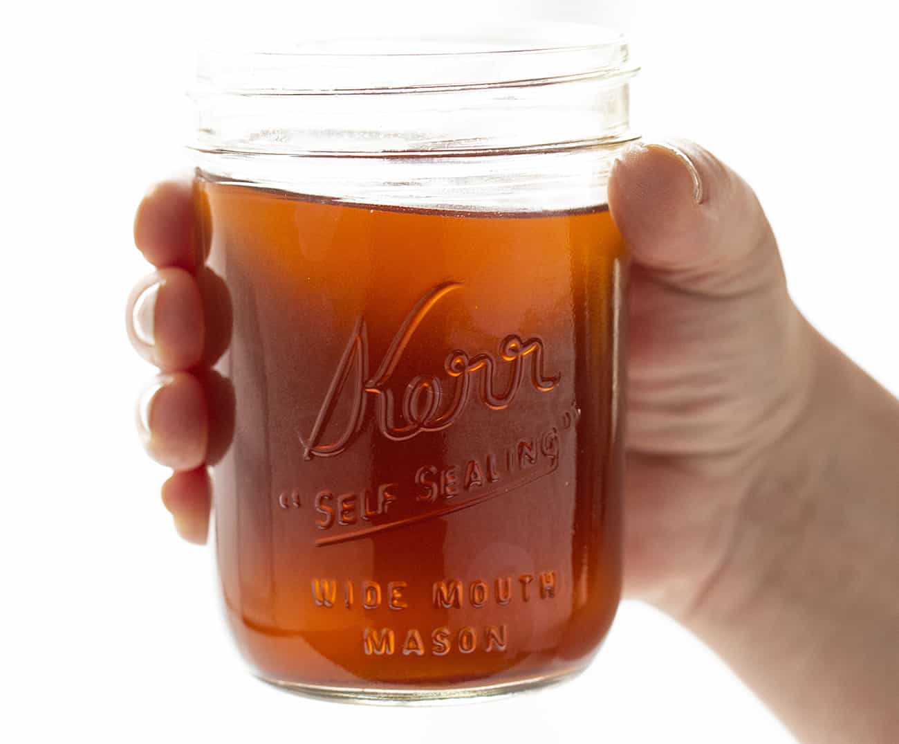 Mano sosteniendo el tarro de canela manzana Moonshine
