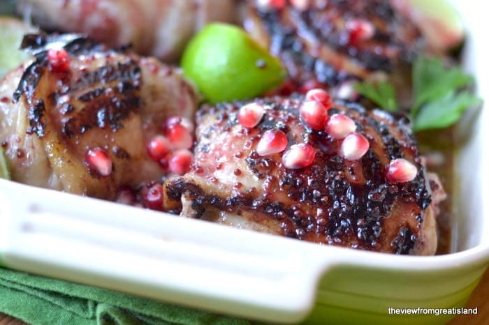 Muslos de pollo glaseados con granada y lima en una fuente para horno verde