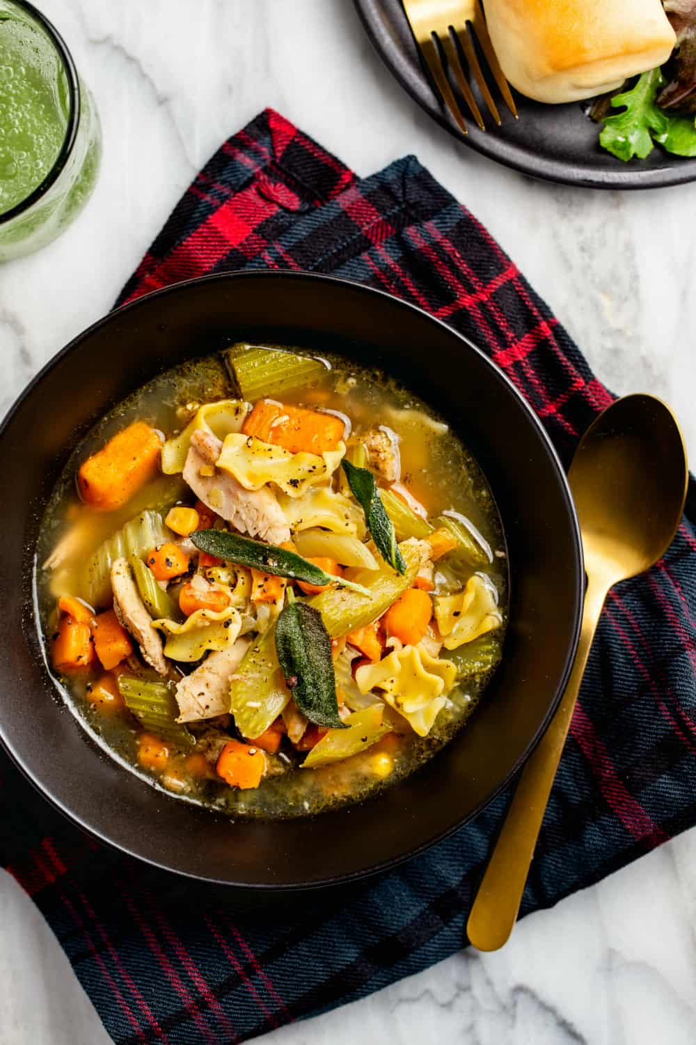 Sopa de fideos de pavo fácil hecha con pavo sobrante en un recipiente negro con una cuchara de oro