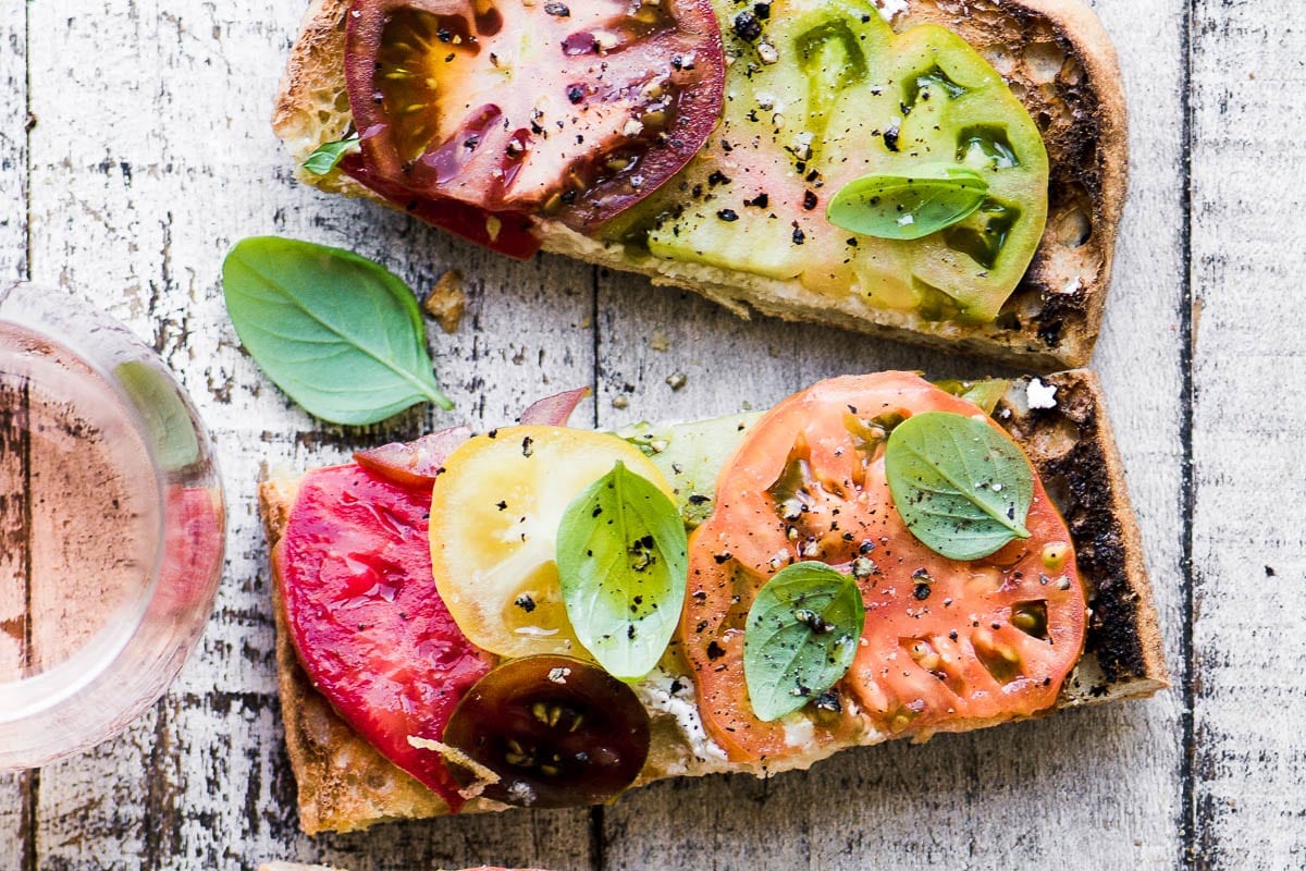 Coloridas tostadas de tomate con una copa de vino rosado