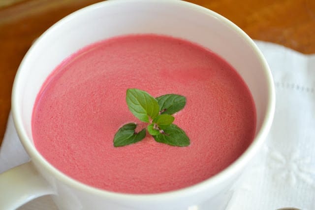 sopa de remolacha fría en una taza blanca, con una ramita de menta