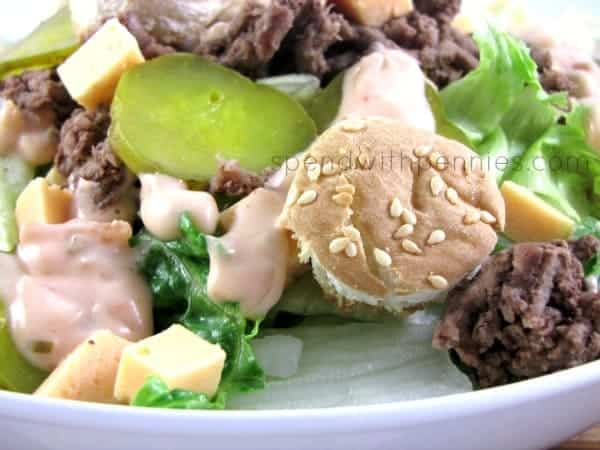 closeup of big Mac salad with pickles, cheese, lettuce, beef and bun croutons topped with dressing in a white bowl