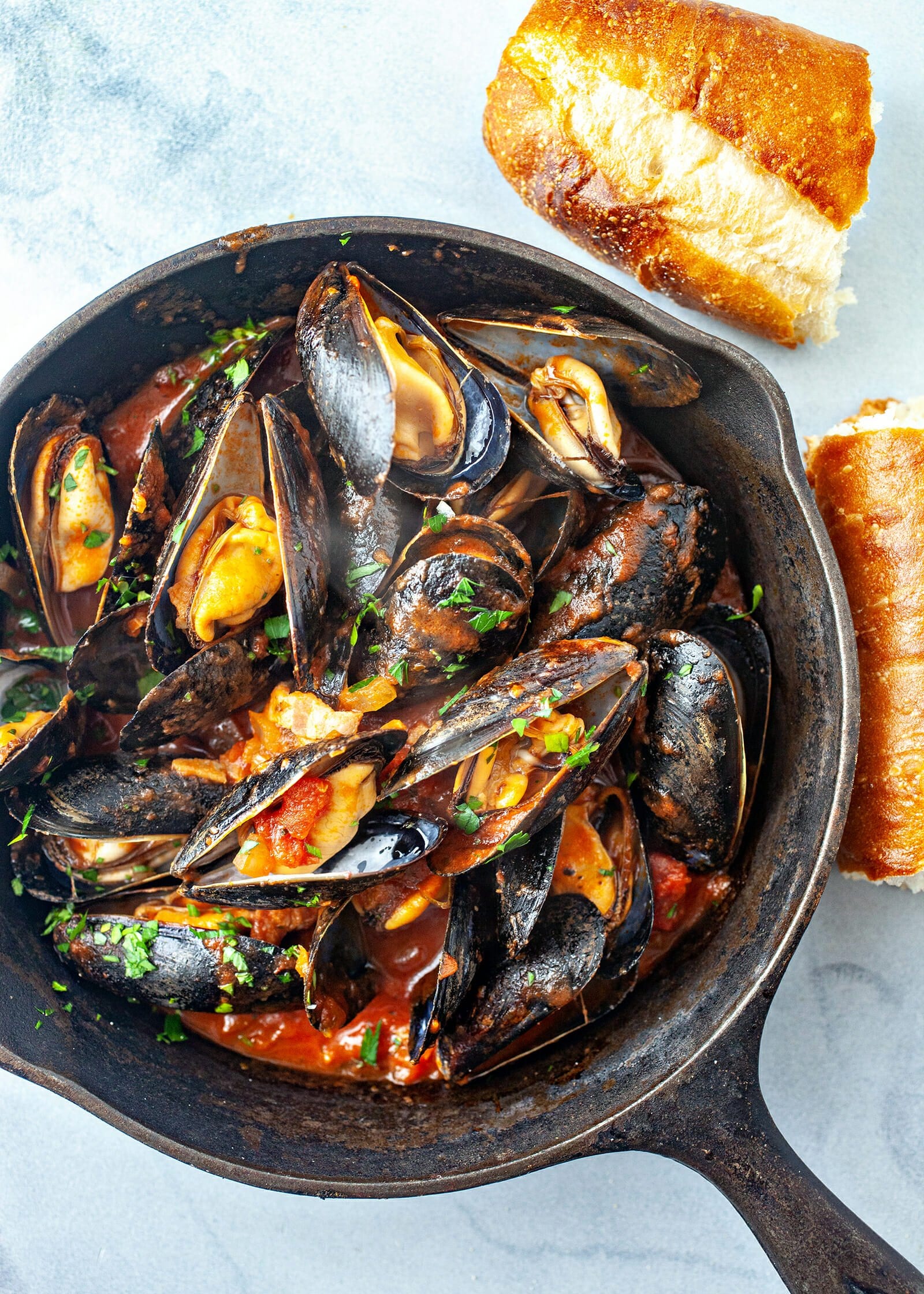 Steamed Mussels in Tomato Sauce - mussels in cast iron pan with baguette