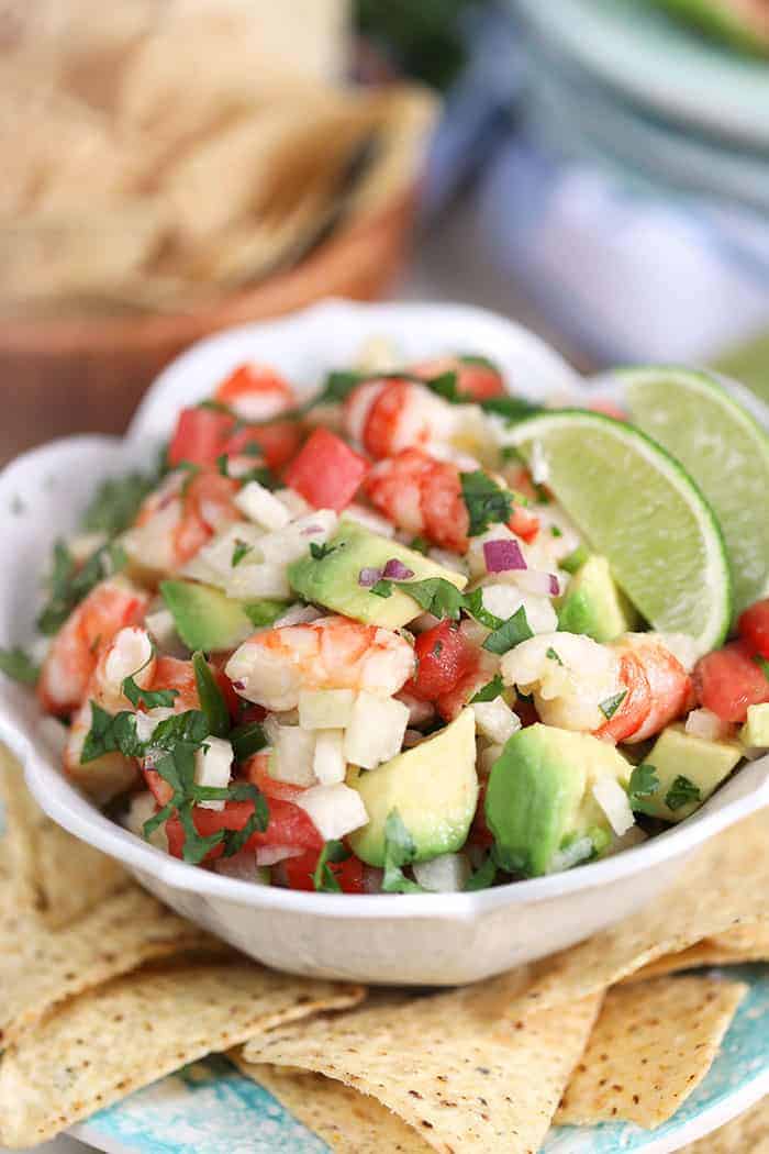 shrimp ceviche with lime in a white bowl with chips and lime garnish