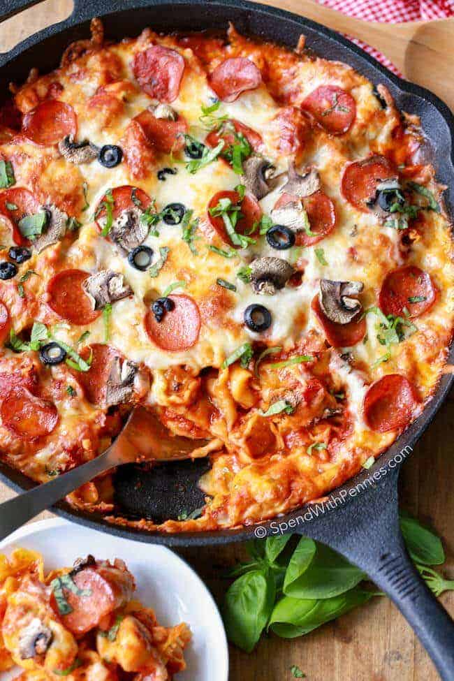 Overhead shot of Pizza Tortellini Bake in black pan with serving spoon in it