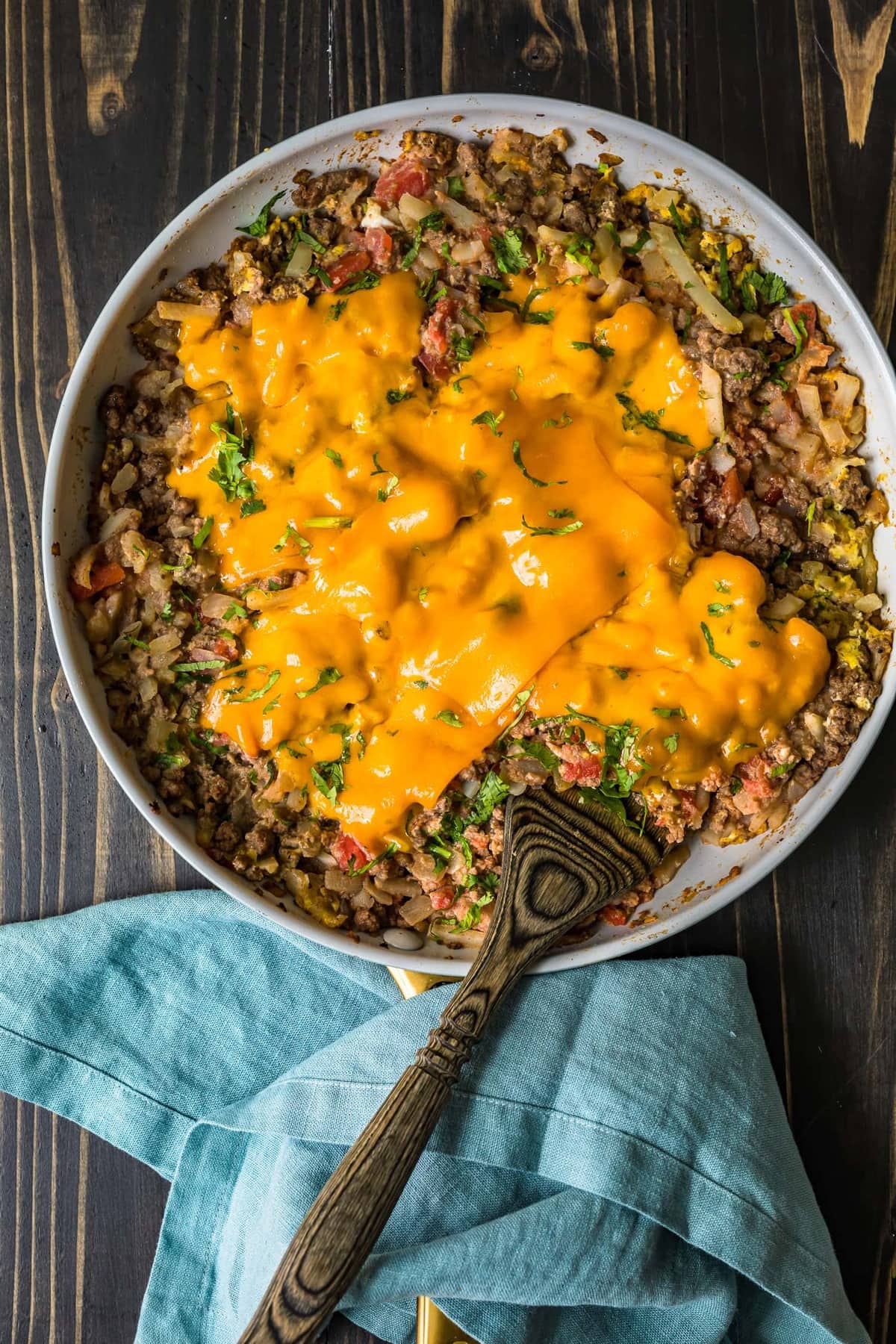 Scramble de café da manhã de carne em uma frigideira branca sobre um fundo de madeira