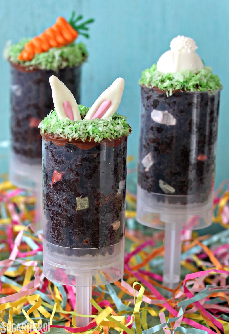 Empurre pops de bolo de Páscoa - Três pops de bolo separados, mostrados com orelhas de coelho, cauda de coelho e cenoura por cima. O | From SugarHero.com