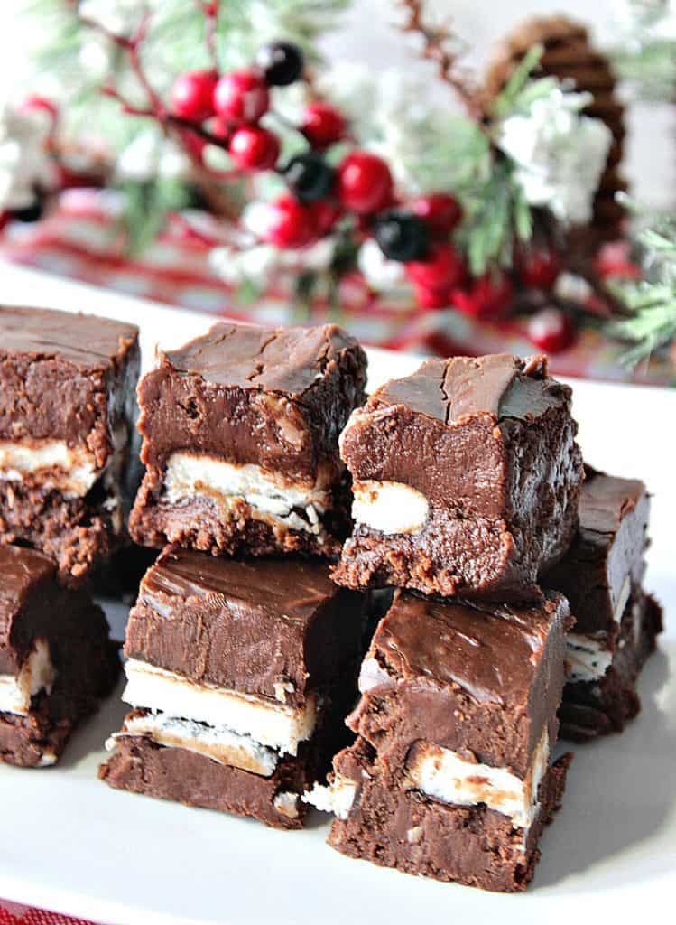 Foto vertical de chocolate com menta chocolate e caramelo de chocolate doce em um prato com hortaliças de Natal em segundo plano.