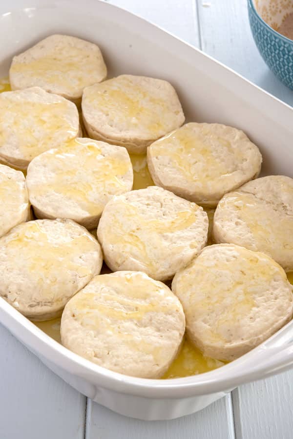 Biscoitos crus em uma assadeira regados com manteiga antes de assar