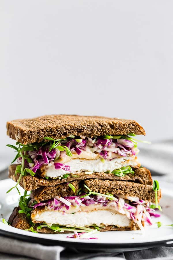 Este sanduíche de frango com repolho crocante e repolho de maçã pega os sabores do outono e os coloca em um sanduíche. É uma costeleta de frango crocante perfeitamente cozida, coberta com queijo Gouda defumado, brotos de ervilha e uma salada de repolho picante de maçã vermelha. Você vai adorar esse sanduíche matador.