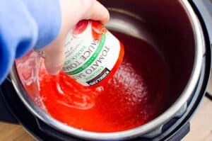 adicionando uma lata de molho de tomate à panela instantânea