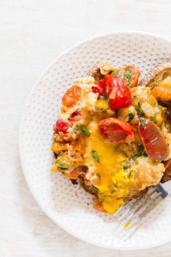 Estes ovos cozidos com bruschetta são o complemento perfeito para o brunch de fim de semana. Tomate refogado misturado com muito alho, manjericão e orégano e coberto com ovos e queijo parmesão. Sirva com torradas e aproveite seu fim de semana! 