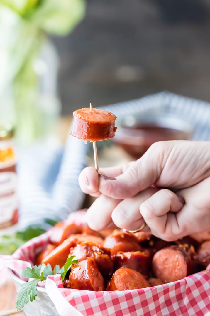 Mão segurando uma mordida de salsicha kielbasa em um palito de dente