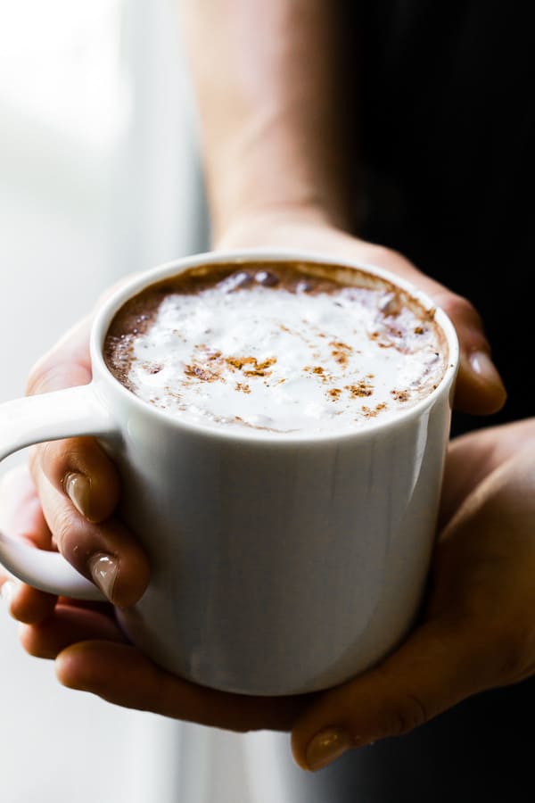 Este doce e cremoso Vitamix chocolate quente está pronto em apenas 5 minutos e é feito completamente em seu Vitamix. Combine chocolate semi-doce, pó de café expresso, extrato de baunilha e apenas uma pitada de canela. Você vai adorar este chocolate quente simples e delicioso!