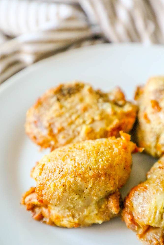 Imagem de uma coxa de frango crocante marrom dourada num prato branco