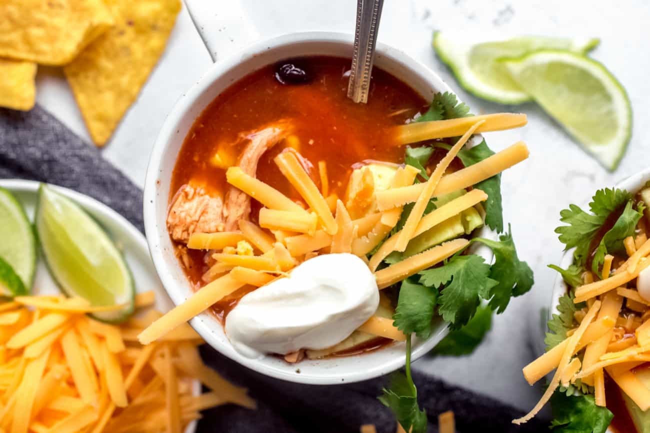 Colher em uma xícara branca de sopa de tortilla com queijo e creme de leite