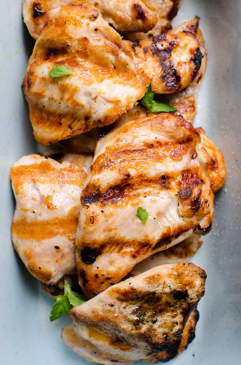 Peito de frango grelhado em um prato decorado com ervas