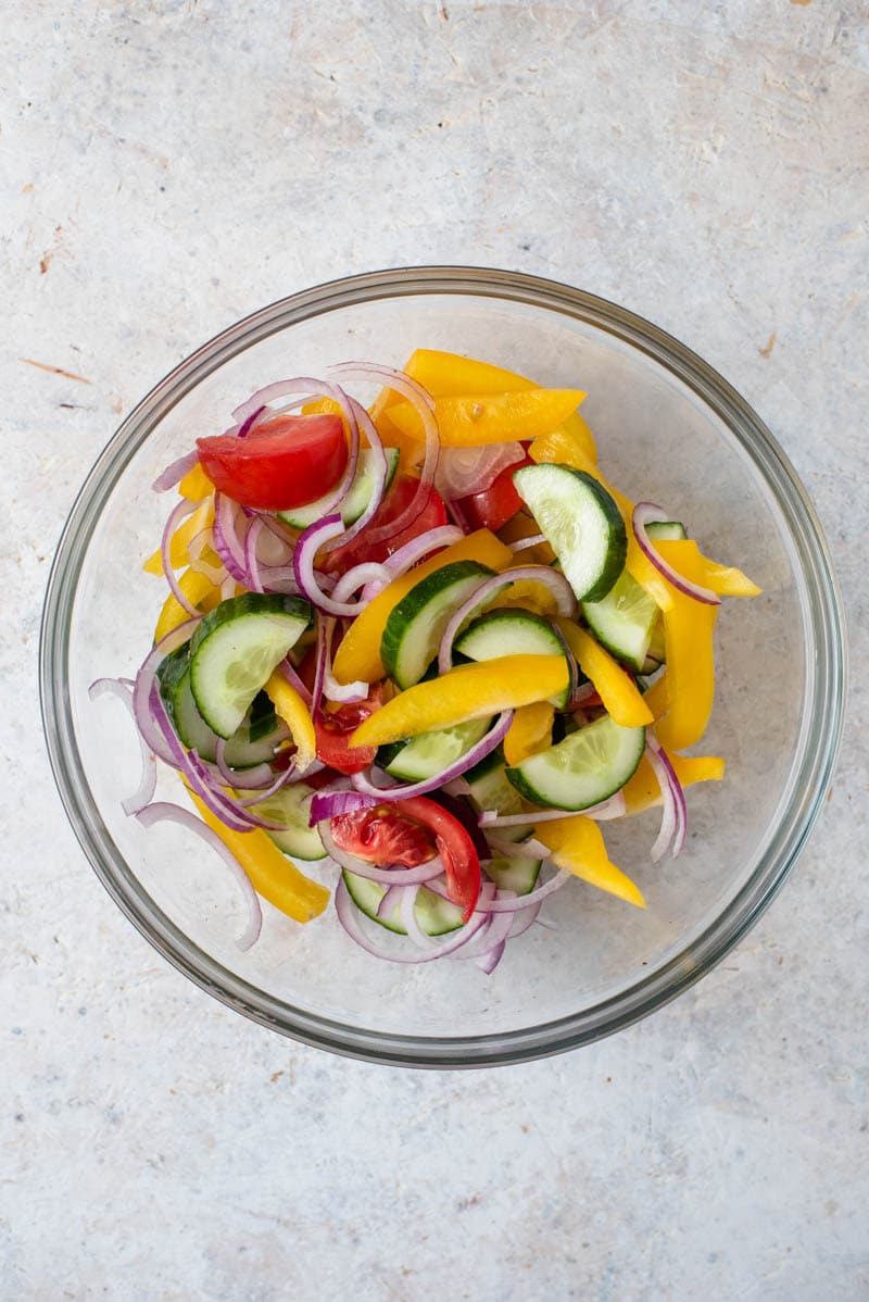 Esta saborosa salada de panzanella (também conhecida como salada de pão) é super fácil, fresca e deliciosa! É feito com um vinagrete de limão Meyer, preparado no processador de alimentos e com um sabor incrível! #salad #panzanella Legumes em uma tigela de vidro para fazer salada de panzanella