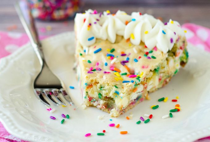 Bolo de biscoito de açúcar Funfetti: macio e amanteigado no centro, crocante nas bordas e cheio de gotas de chocolate branco e granulado para comemorar qualquer ocasião. Coberto com um creme amanteigado de manteiga de baunilha e amêndoa.