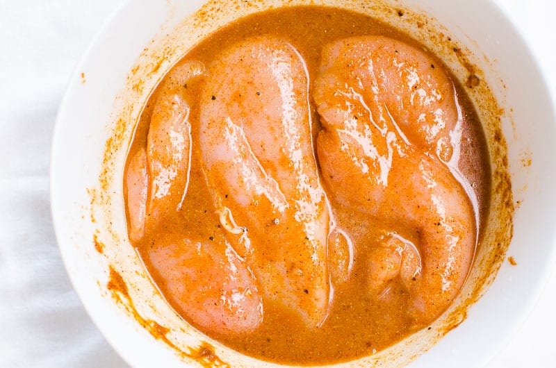 Marinada de frango com pimenta em uma tigela com peitos de frango
