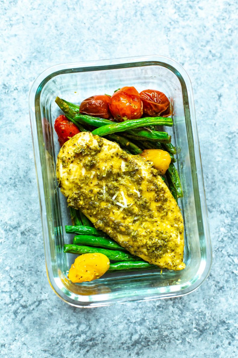Pollo con salsa de pesto y verduras cocidas en un recipiente de preparación de comida de vidrio
