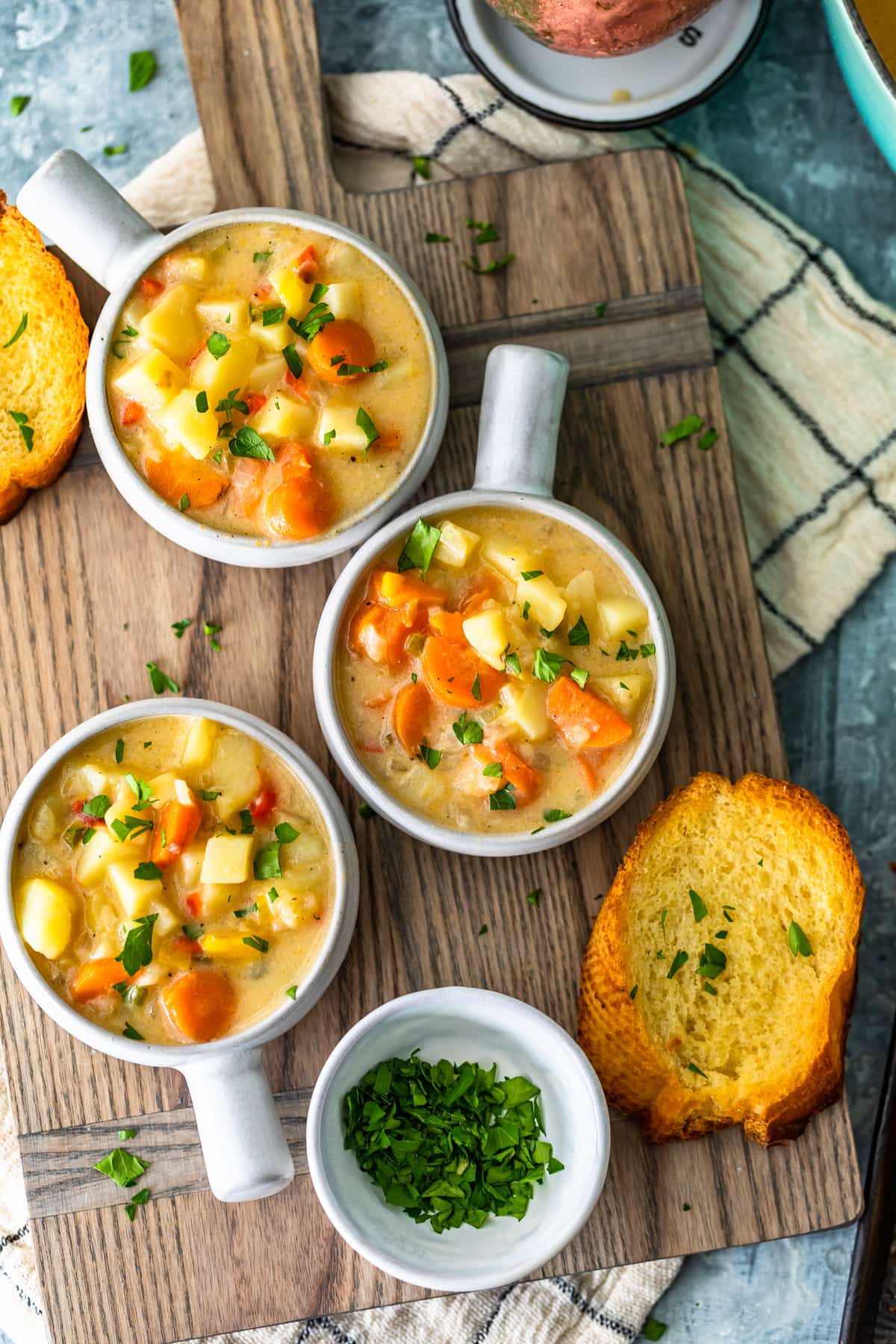 tres tazones de sopa de papa en una tabla para cortar madera