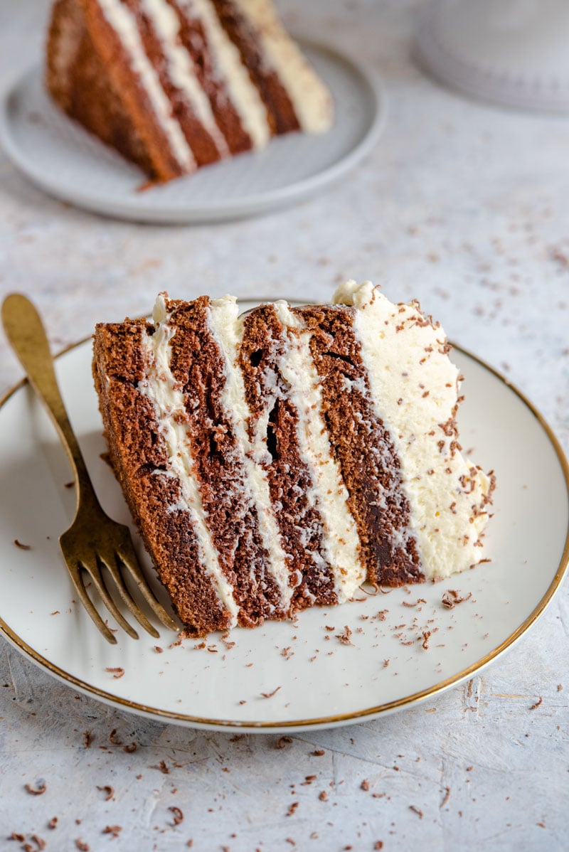 Uma fatia grande de bolo de chocolate num prato com cobertura de baunilha
