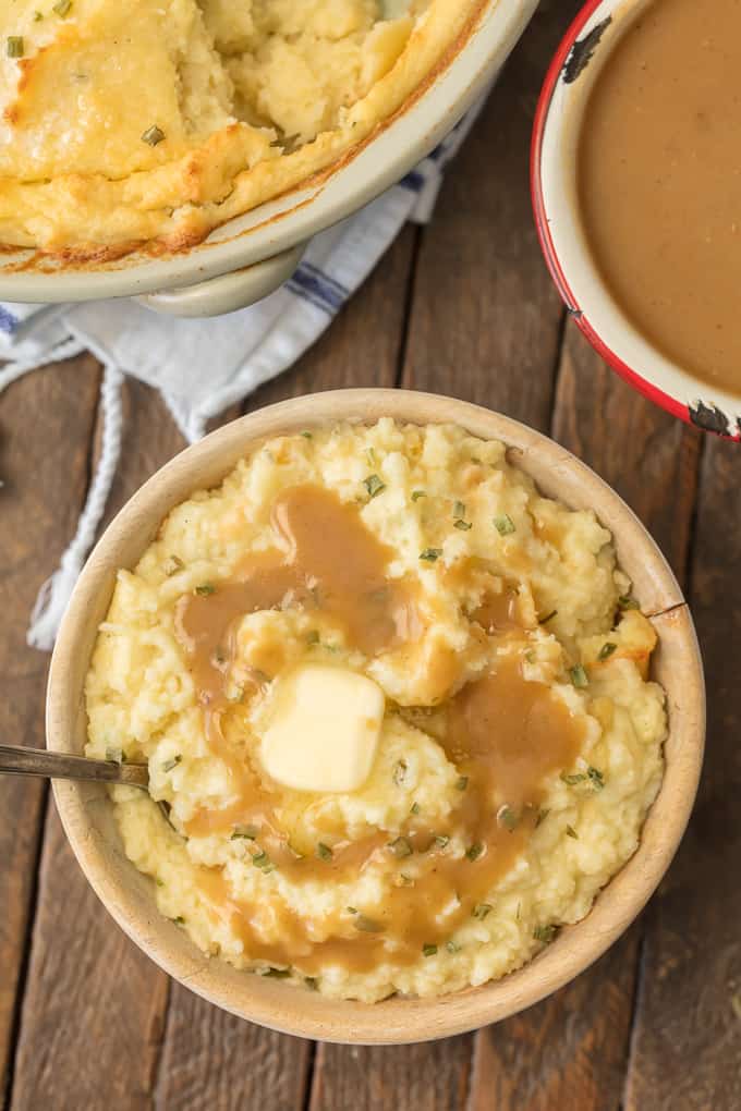 ¡Make Ahead Mashed Potatoes son las mejores papas a la crema para su mesa festiva! ¡Haga que las vacaciones sean fáciles con esta RECETA DE PATATAS MASHED! Esta cazuela de puré de papa cremosa y soñadora es TAN SENCILLA para que no tengas que quedarte atrapado en la cocina este Día de Acción de Gracias. un tazón de puré de papas cubierto con salsa y un poco de mantequilla